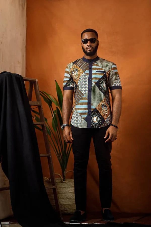 Man in patchwork Ankara short-sleeve shirt with mandarin collar and black trousers