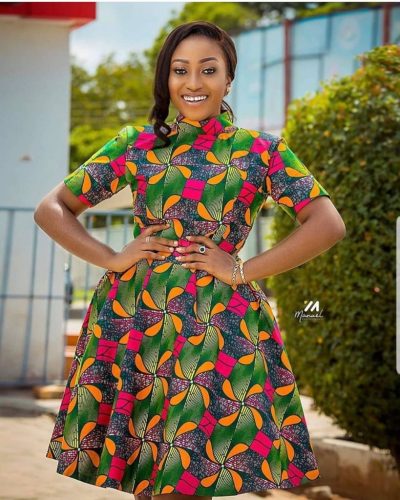 Model in green, pink, and orange Ankara A-line dress with mock neck