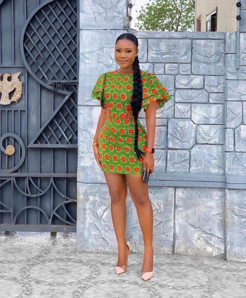 Model in green floral Ankara bodycon dress with waist cut-outs and flutter sleeves