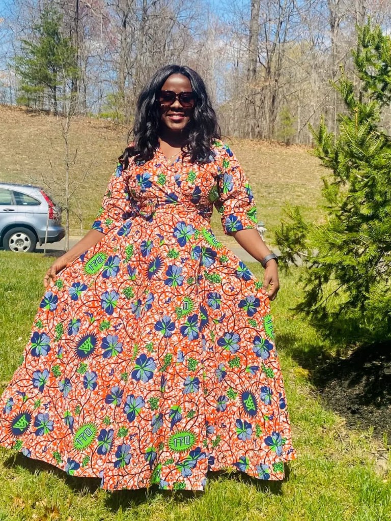 Model in orange floral Ankara wrap maxi dress on a lawn